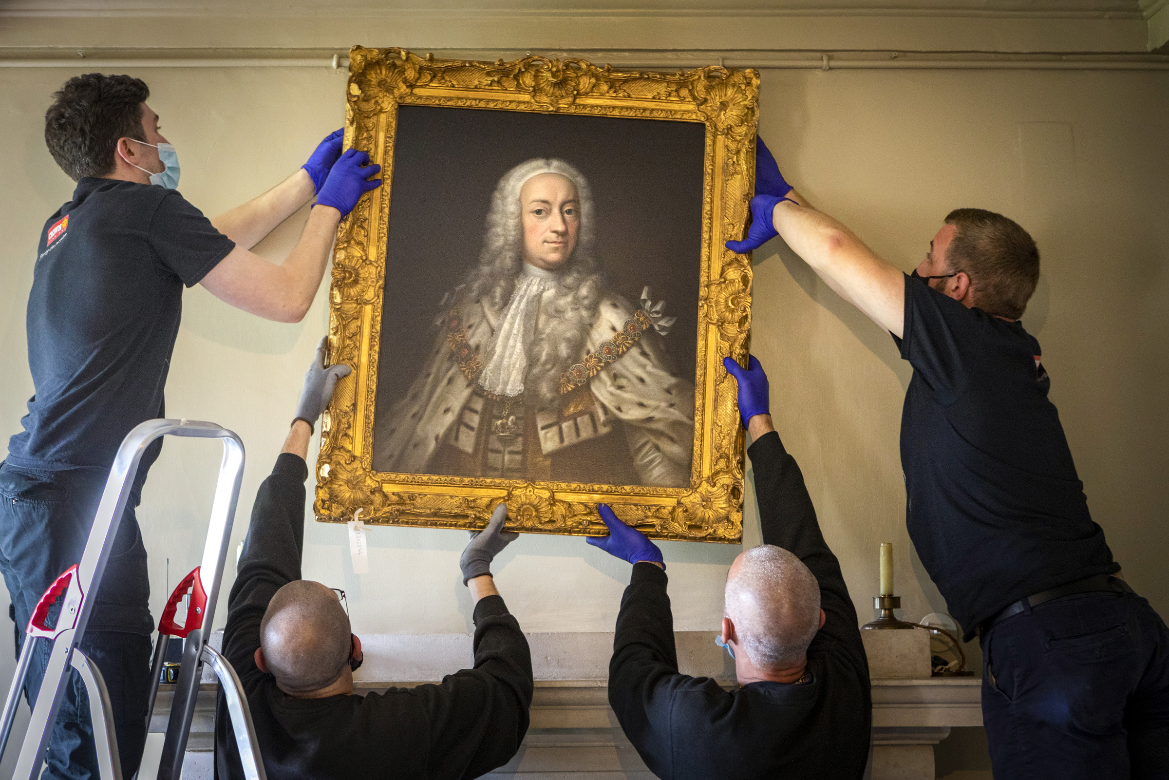Contractors rehang a painting at Marble Hill